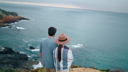 Fototapeta premium Romantic couple walking sea shore back view. Pair looking on picturesque ocean.