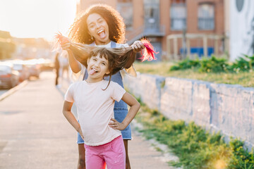 Young nanny and cute girl having fun together outside. Children activities together, babysitting concept