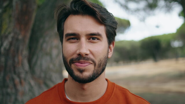 Portrait happy bearded man looking camera with smile at beautiful forest alone.