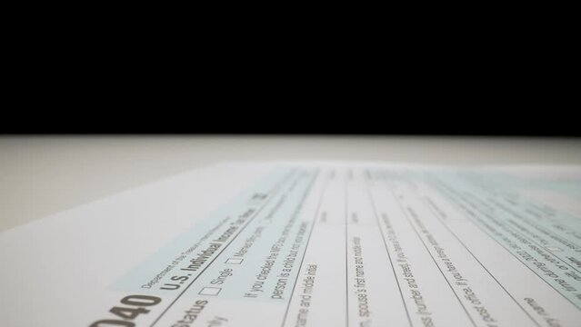 Closeup macro shot movement shot of blank 1040 tax form paper for corporate accountant or individual tax payer with pen preparing for tax season and submitting financial report.