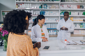 Asian woman pharmacist selling drugs to an african american customer in a pharmacy