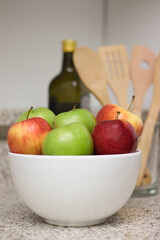 Three red apples and three green apples in a bowl at the kitchen