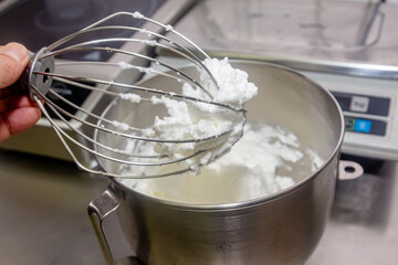 Fototapeta na wymiar Mixing white egg cream in bowl with motor mixer, baking cake