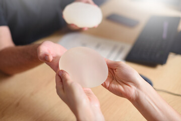 Doctor offers breast augmentation implants to a woman - obrazy, fototapety, plakaty