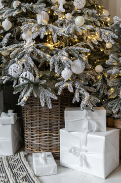 White gift boxes near a snowy Christmas tree and with a fairy-tale Christmas decoration.