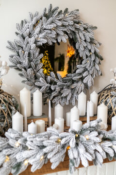 The fireplace is decorated in a New Year's style. Many lights of Christmas trees and lighted candles. Snow-white decor and family coziness