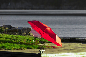 red umbrella left on a pier