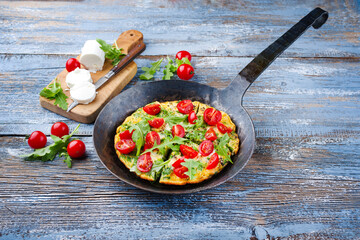 Traditional German vegetarian rucola omelet with cherry tomatoes and cream goat cheese served as...