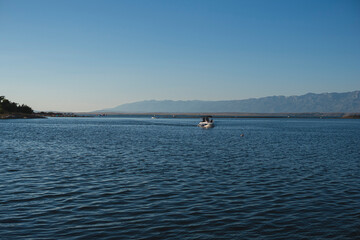 Obraz premium landscape with a boat on the adriatic sea with velebit mountains on the background