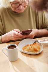 senior woman using her cell phone at breakfast