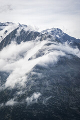 snow covered mountains looking through the fog and clouds 