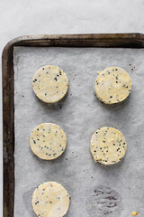 Raw black sesame scones dough on a parchment lined tray, black sesame scones dough about to be baked, process of making scones