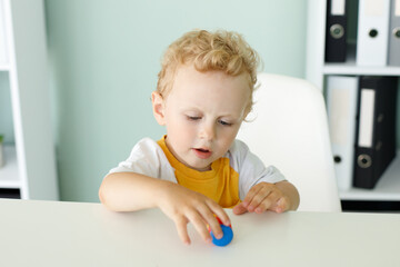 portrait of a cute blond boy playing at the table