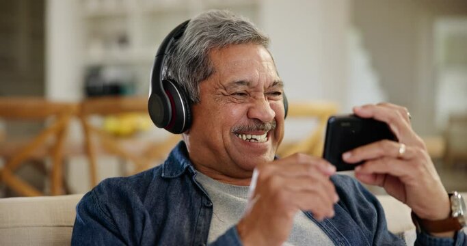 Laughing, senior man and a movie on a phone, watching a funy video or film on the internet. Happy, streaming and an elderly person with headphones, mobile and a comedy show on an app on the home sofa
