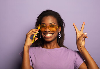 Portrait of young afro woman holding in hands smartphone isolated over violet background