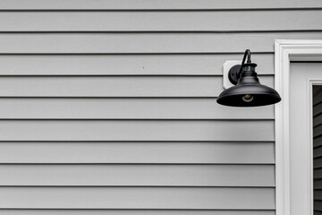 Metal Black Modern Farmhouse Light Sconce on Home Deck Exterior with Grey Siding and Copyspace
