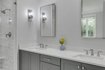 Clean Luxury Modern Primary Bathroom Interior Vanity with Double His and Her Sinks and Floral Arrangement in Vase. Double Mirrors and Glass Standing Shower