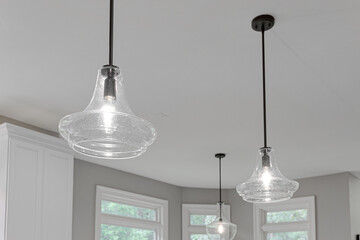 Clear Penant Lights Over Kitchen Island with Black Metal Rod in Blank Ceiling - obrazy, fototapety, plakaty