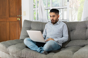 Young man sitting on the couch using a laptop computer.
