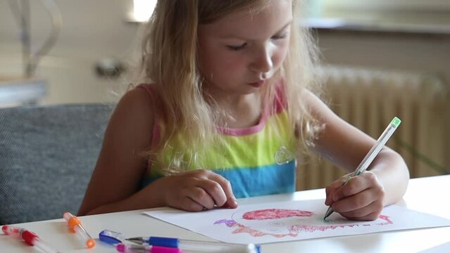Little girl draws on paper.