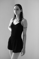 Black and white portrait of a brunette girl without make up on a grey backgroung in a black summer clothes