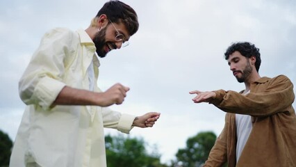 `Romantic Lgbt couple in great mood playing around and dancing, feeling love and freedom. Happy carefree gay guys dancing and hugging in the park together, enjoying recreation time on weekend.