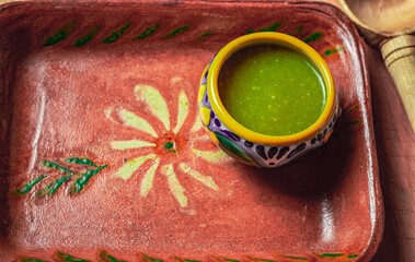 Comida mexicana, salsa verde sobre un recipiente de talavera, montado sobre un plato tradicional de...
