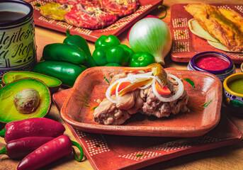 Platillo tradicional mexicano, carne de cerdo condimentada, acompañada de chiles y tomates sobre...