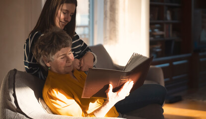 Grandmother and her granddaughter spend time together looking at photos from an album.