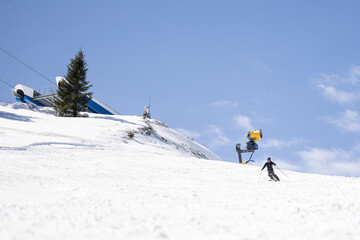 Professional skier skiing on slopes in a mountain winter resort. Sunny day with clear sky.