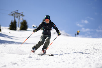 Fototapeta na wymiar Professional skier skiing on slopes in a mountain winter resort. Sunny day with clear sky.