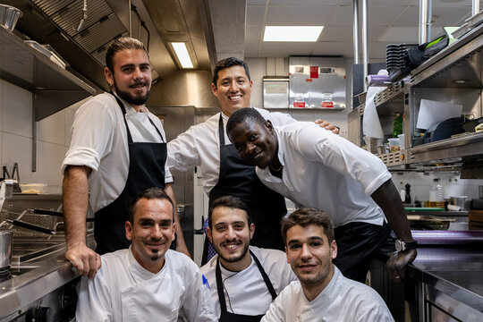 Multi ethnic cooking team looking at the camera while taking a team photo