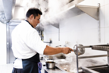 South American chef is cleaning the kitchen grill with water and it causes a lot of smoke