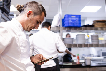 Chef with a dread pigtail is looking at his mobile phone to look for a recipe