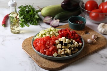 Cooking delicious ratatouille. Fresh ripe vegetables and plate on white marble table