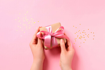Woman with gift box and confetti on pink background, top view