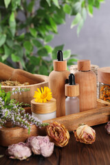 Fototapeta na wymiar Jar, bottles of essential oils and different herbs on wooden table