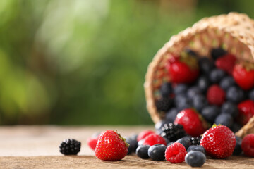 Different fresh ripe berries on wooden table outdoors. Space for text