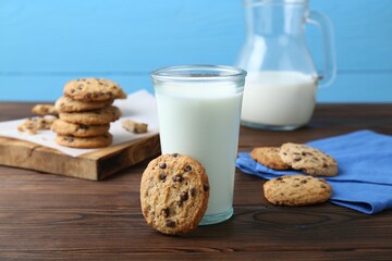Delicious chocolate chip cookies and glass of milk on wooden table