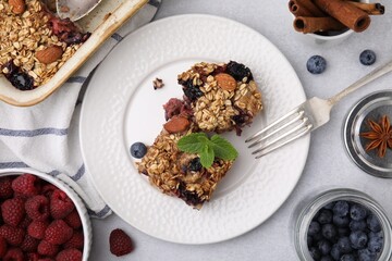 Tasty baked oatmeal with berries and almonds on light grey table, flat lay