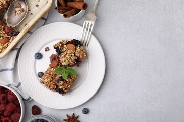 Tasty baked oatmeal with berries and almonds on light grey table, flat lay. Space for text