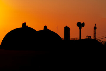 Silhouette of San Onofre nuclear power plant main reactors and alarm siren at sunset with sun...