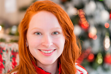 Christmas portrait of a beautiful young red-haired woman with grey eyes against a background of Christmas decorations