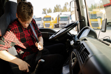 Young truck driver putting safety belt on , closeup of man in cabin