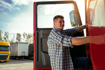 Middle age Caucasian man, truck driver entering a truck and looking at camera