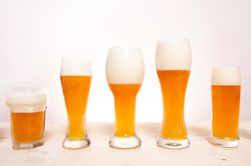 Glasses full of beer with foam on wooden table with clean background 