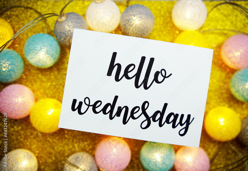 Poster hello wednesday text on paper card top view on yellow bokeh background