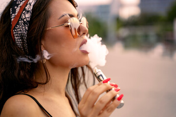 Closeup shot of amazing beautiful young girl using e cigarette, puffing smoke 