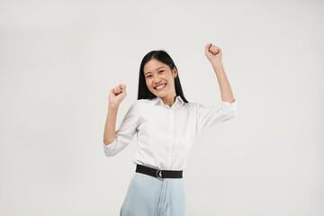Happy young Asian woman raising his fists doing yes gesture, isolated on soft grey background.