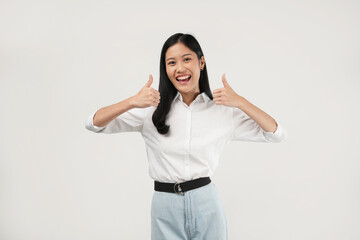 Photo of a young Asian girl wearing casual white clothes smiling and doing thumb up, and approval sign.